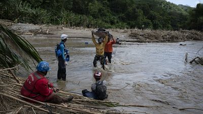 Rescuers cross the Tuy river as they search for victims of a devastating landslide in the Venezuelan town of Las Tejerias.