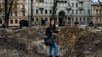 A woman poses for a photograph by a rocket crater in a park of central Kyiv.