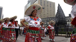 Women dressed in traditional costumes pass the statue of Christopher Columbus on 12 October 2004