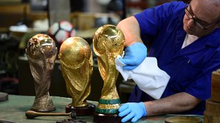 An artisan operator cleans with a cloth a replica of the FIFA football World Cup Trophy.