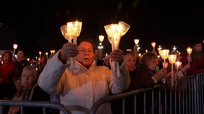 Pilgrims holding candles and chanting as the statue of Our Lady of Fatima passes through the crowd.
