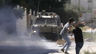 فلسطيني يرشق الحجارة على سيارة عسكرية إسرائيلية في جنين بالضفة الغربية المحتلة. 2022/09/28
