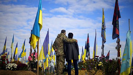 DATEI - Eltern eines kürzlich getöteten ukrainischen Soldaten stehen neben seinem Grab, 14. Oktober 2022.