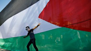 شاب فلسطيني يقف أمام علمه الوطني خلال احتفالات في مدينة غزة. 2017/10/12