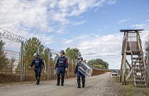 Operational police officers walk along the service route of Hungary's border with Serbia near Roszke, Southern Hungary.