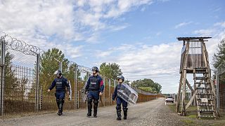 Operational police officers walk along the service route of Hungary's border with Serbia near Roszke, Southern Hungary.