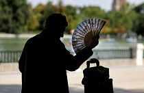 A man uses a hand fan in a park in central Madrid during a heatwave, on August 2, 2022. Heatwaves kill thousands of people every year.