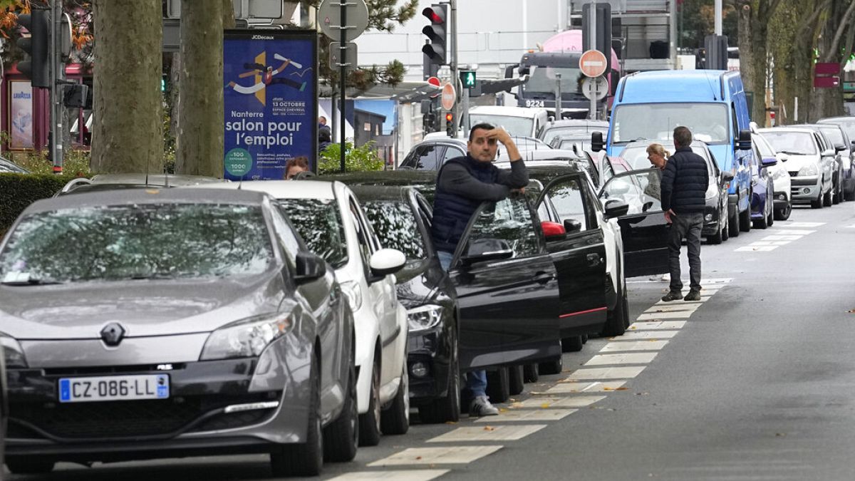 A man stands by his car as he waits to reach a petrol station in Nanterre, France