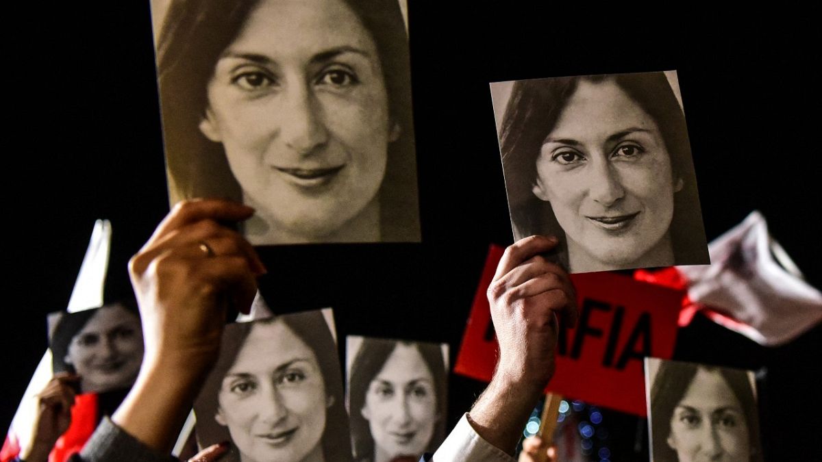  In this file photo taken on November 29, 2019 shows people holding placards reading "Mafia Government" and photos of killed journalist Daphne Caruana Galizia.