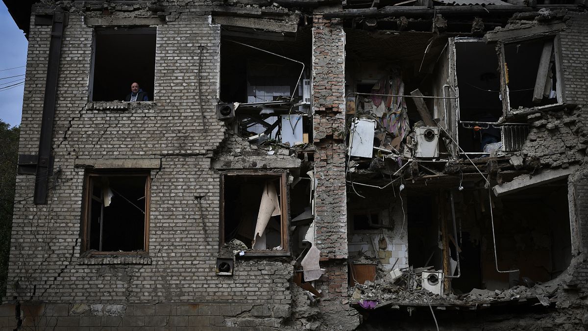 Orosz rakétacsapásban megrongálódott lakásának ablakából néz ki egy férfi a kelet-ukrajnai Konstantinovkában 2022. október 14-én