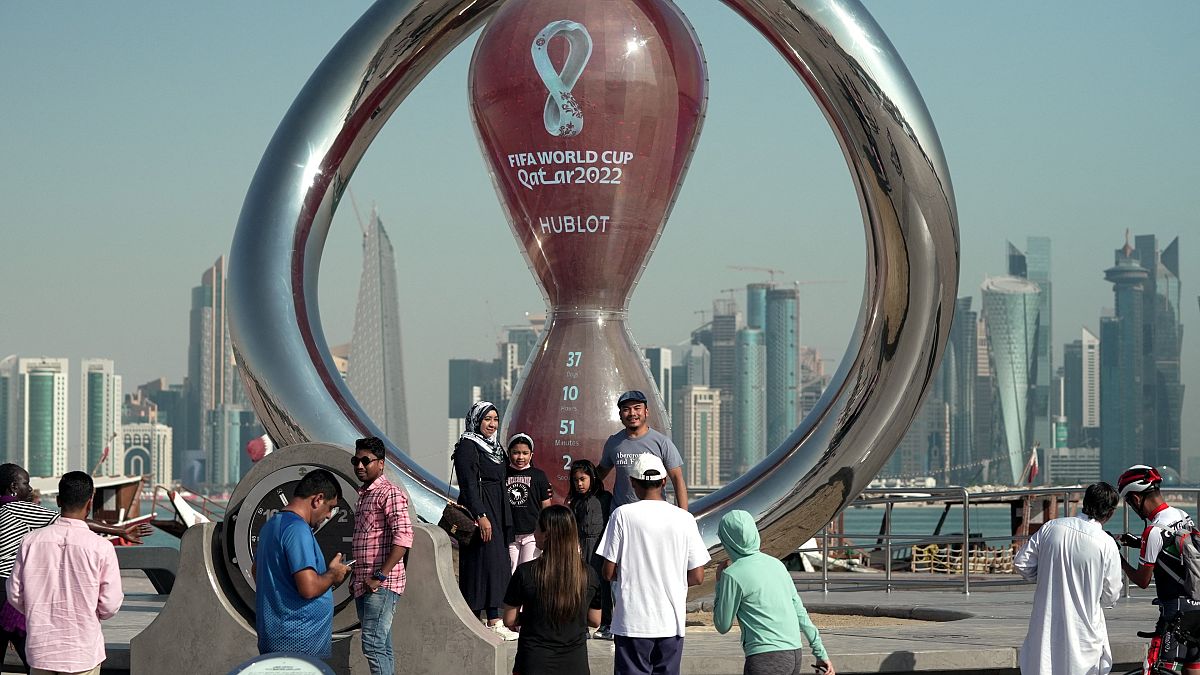 أناس يقفون لالتقاط صورة تحت ساعة العد التنازلي لكأس العالم في العاصمة القطرية الدوحة. 2022/10/14