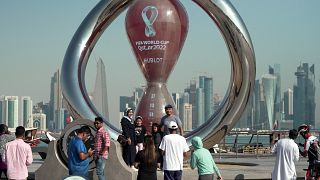 أناس يقفون لالتقاط صورة تحت ساعة العد التنازلي لكأس العالم في العاصمة القطرية الدوحة. 2022/10/14