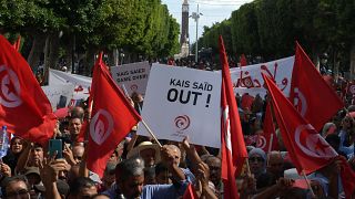 Menschen schwenken Nationalflaggen und halten Plakate hoch bei einer Demonstration gegen Präsident Kais Saied in der Hauptstadt Tunis