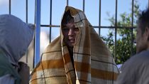 An Afghan covered with a blanket, speaks with other migrants at an old school used as a temporary shelter on the island of Kythira, southern Greece, 7 October 2022
