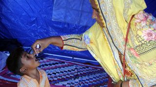 A health worker administers a polio vaccine to a child at a camp in Hyderabad, Pakistan, Tuesday, Sept. 6, 2022.