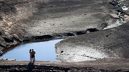 A couple stands on what was an ancient packhorse bridge exposed by low water levels at Baitings Reservoir in Yorkshire, England, Aug. 12, 2022.