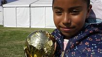Una pequeña aficionada posa con una réplica de Copa del Mundo, presente estos días en México
