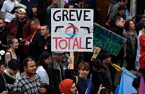 A protester holds a placard reading 'Total strike' -a play on the French energy giant TotalEnergies- during a rally in Paris on October 16, 2022.