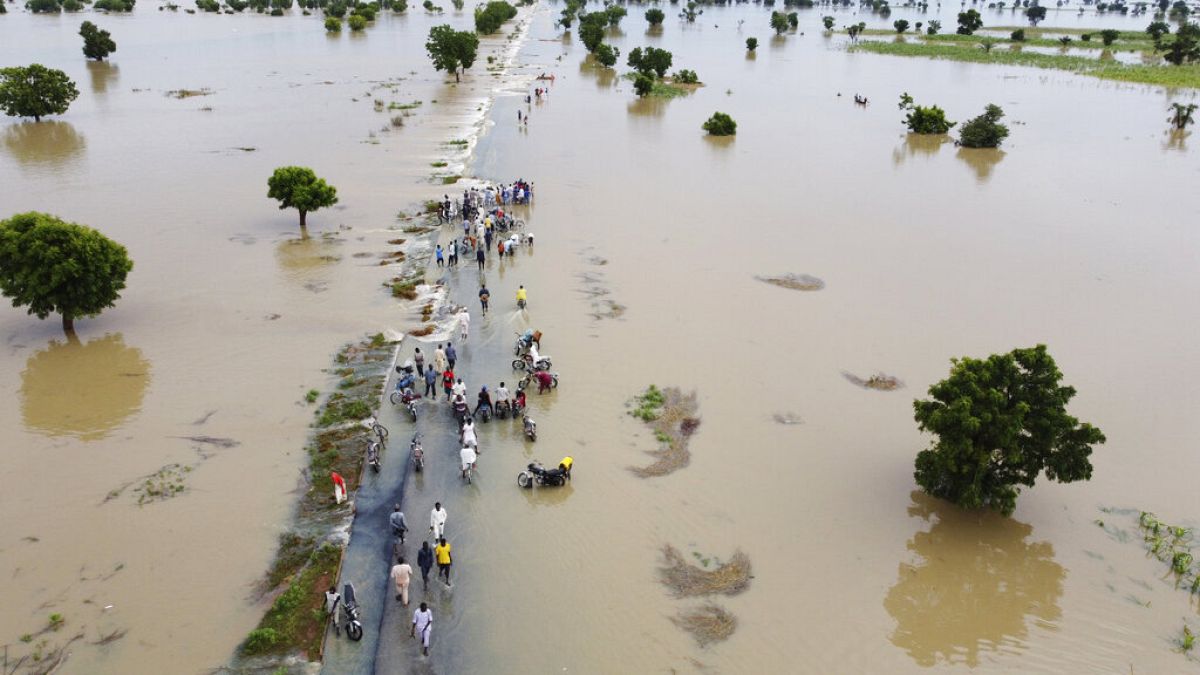 People walk through floodwaters after heavy rainfall in Hadeja, Nigeria, Monday, Sept 19, 2022