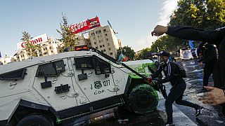 Demonstrators attack a police armored vehicle during clashes on the three-year anniversary of the start of anti-government protests, in Santiago, Chile, Tuesday, Oct. 18, 2022