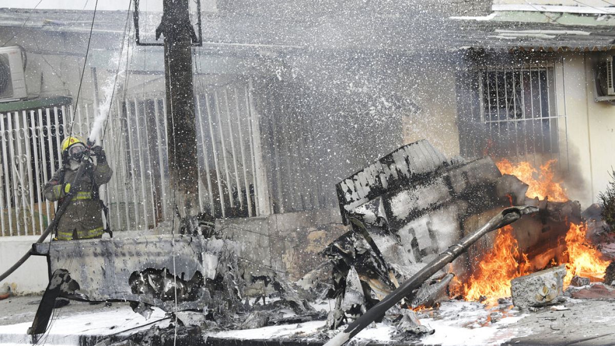 Un bombero extingue los restos de una avioneta que se estrelló en un barrio de Guayaquil, Ecuador, el martes 18 de octubre de 2022.
