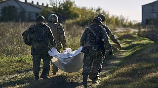 Ukrainian servicemen carry an exhumed body in the recently retaken village of Shandryholove, the Donetsk region, Ukraine, Sunday, Oct. 16, 2022.
