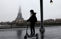 A woman rides a scooter in Paris in front of the Eiffel tower, January 27, 2021.
