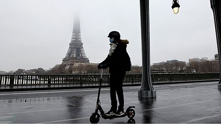 A woman rides a scooter in Paris in front of the Eiffel tower, January 27, 2021.