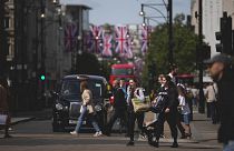 People carrying shopping bags cross the Oxford Street shopping district.