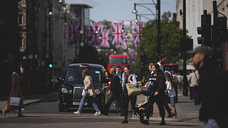 People carrying shopping bags cross the Oxford Street shopping district.