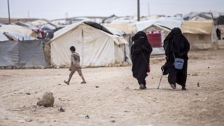 Women walk in the al-Hol camp that houses some 60,000 refugees, including families and supporters of the Islamic State group. 1 May 2021.