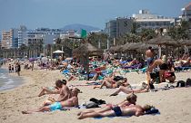 Tourists sunbathe on the beach at the Spanish Balearic Island of Mallorca, Spain.
