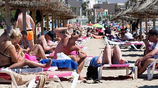 Tourists sunbathe on the beach at the Spanish Balearic Island of Mallorca, Spain.