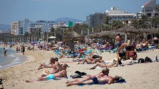 Tourists sunbathe on the beach at the Spanish Balearic Island of Mallorca, Spain.