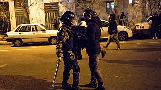 Saturday, Jan. 11, 2020, a protester confronts an Iranian police officer while demonstrators gather in front of Amir Kabir University in Tehran, Iran.