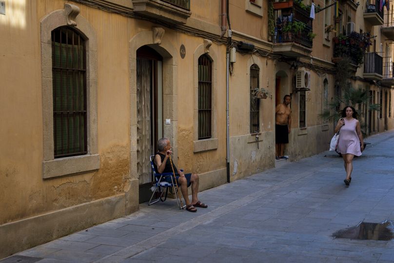 A man sits outside his house on a hot and sunny day in Barcelona.