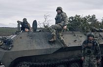 Ukrainian servicemen and a servicewoman, centre, pose for a photo with their armoured vehicle near Bakhmut, 22 October 2022