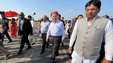 UN Secretary-General Antonio Guterres wearing traditional headgear walks upon his arrival in Modhera.