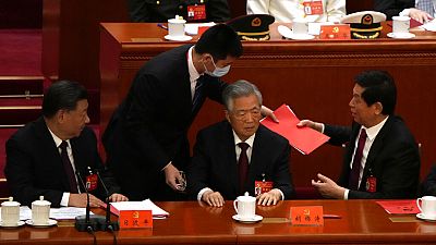 Former Chinese President Hu Jintao, front row second from right, talks to his predecessor as party leader Xi Jinping, right.