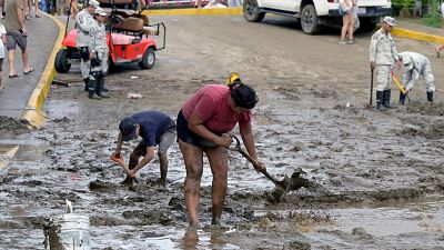People and emergency brigade clean up mud and water from flooded streets in Sayulita.