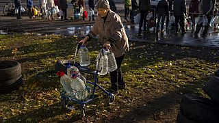 Catherine, 75 ans, pousse son déambulateur chargé de bouteilles en plastique après les avoir remplies dans un réservoir, dans le centre de Mykolaiv - 24.10.2022