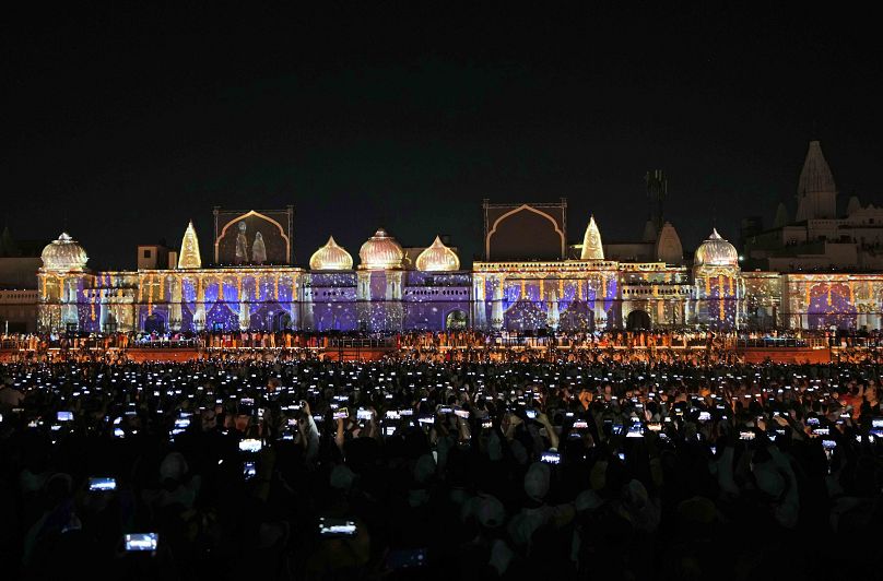 Spectators lift their phones to record a laser show on the life of Hindu God Ram in Ayodhya, India