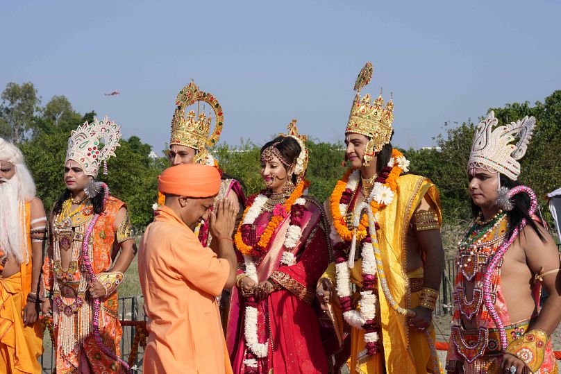 Uttar Pradesh state Chief Minister Yogi Adityanath greets artists dressed as Hindu god Ram, goddess Sita and Lakshman on the banks of river Saryu