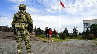  A young couple walks past a Russian soldier in Kherson