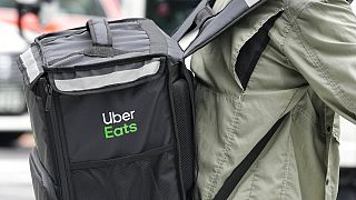 An Uber Eats delivery person rides a bicycle through a commercial district in Tokyo, Japan Tuesday, Aug. 30, 2022.(AP Photo/Shuji Kajiyama)