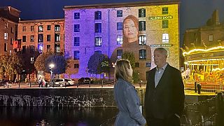 Chris Tarrant and Vladyslava Zhmuro stand in front of Sergey Piskunov's portrait