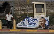 Eski Başbakan Binyamin Netanyahu'nun seçim afişinin önünde otobüs bekleyen bir Yahudi yerleşimci,