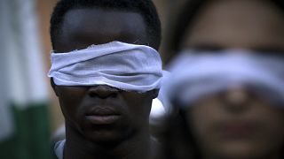 Un homme les yeux bandés durant une manifestation à Rome contre un accord entre l'Italie et la Libye