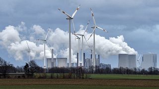 صورة أرشيفية لمولّدات الطاقة بقوة الرياح وخلفها محطة طاقة تعمل بالفحم الحجري، بالقرب من جاكيرات، ألمانيا،  7 ديسمبر، 2018.