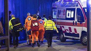 Orvosok egy sérültet mentőautóba tesznek az assagói késes támadás után 2022. október 27-én